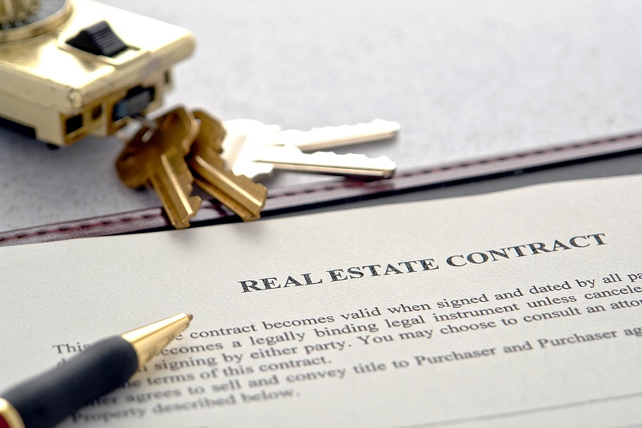 Real Estate Contract with a pen and keys on a table